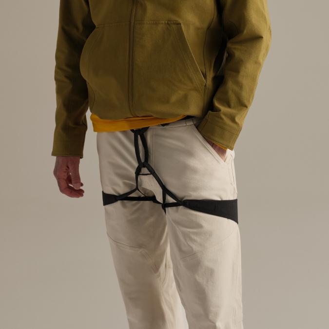 Person wearing an olive jacket, light pants, and a black thigh harness.
