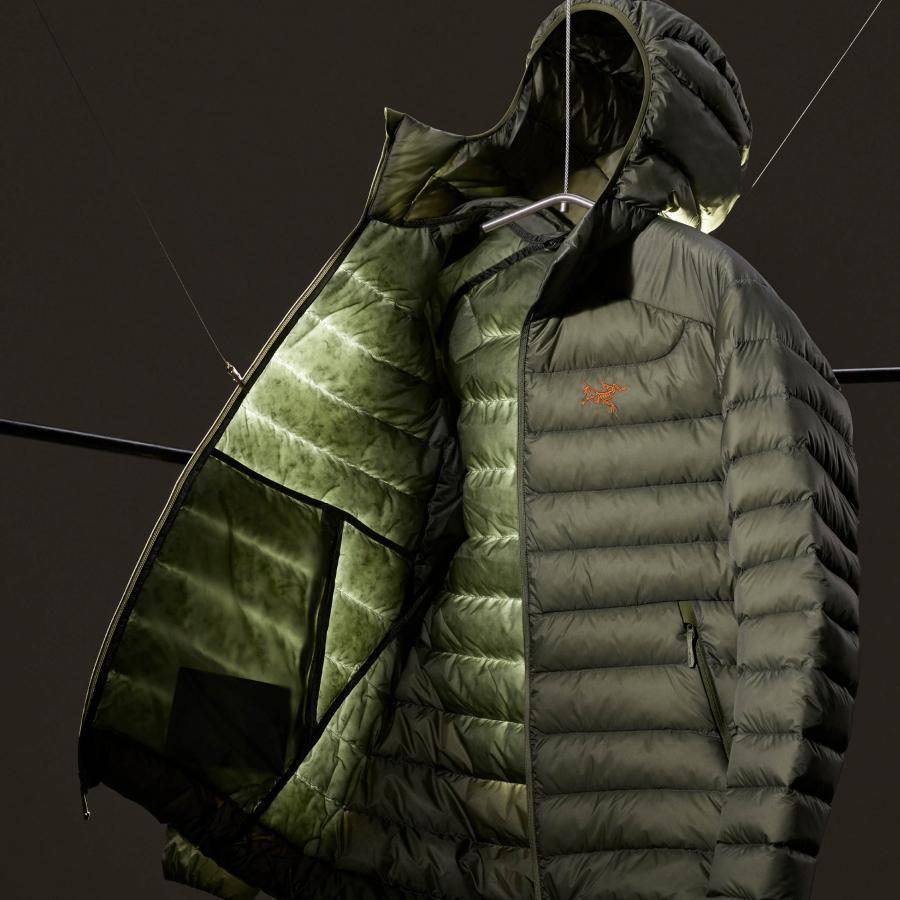 a green jacket with a hood is hanging on a hanger .