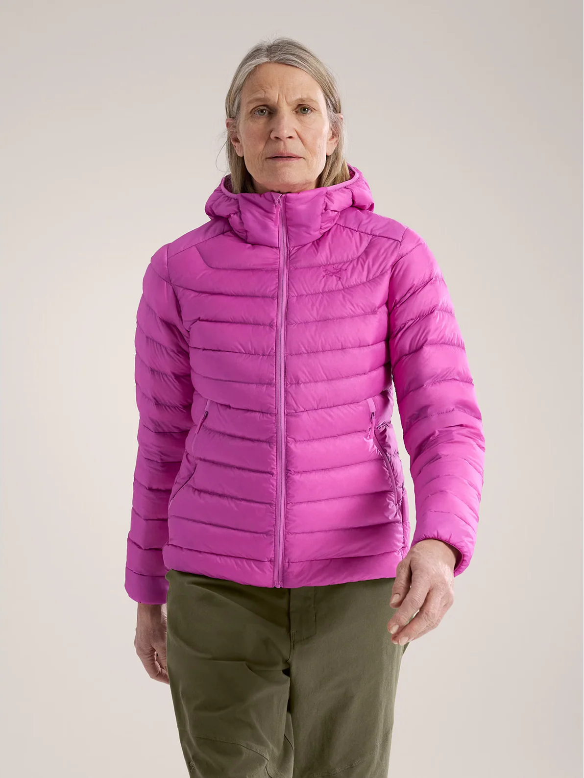A woman wearing a pink hooded puffer jacket and olive green pants.