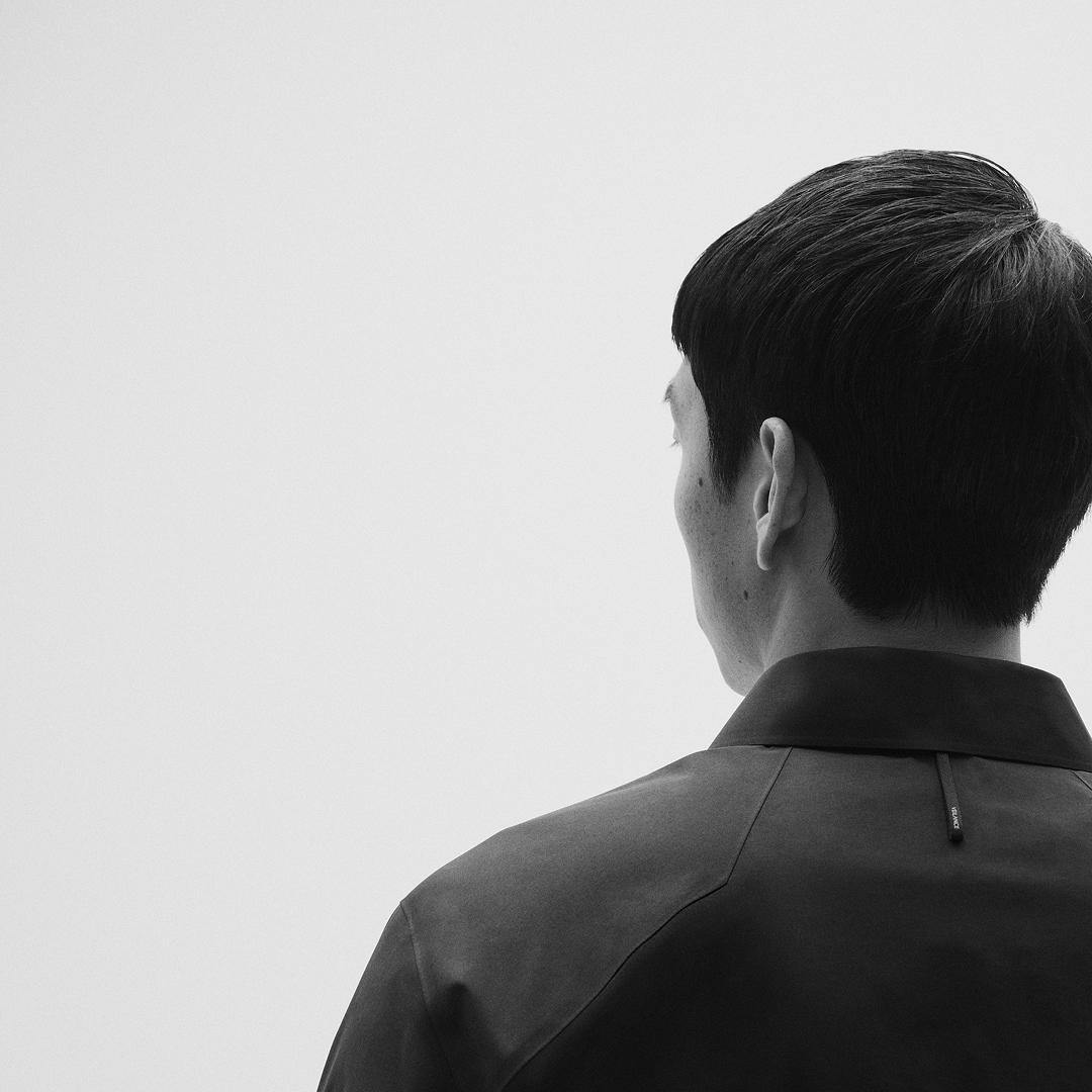 Black and white image of a person's back and head, facing left.