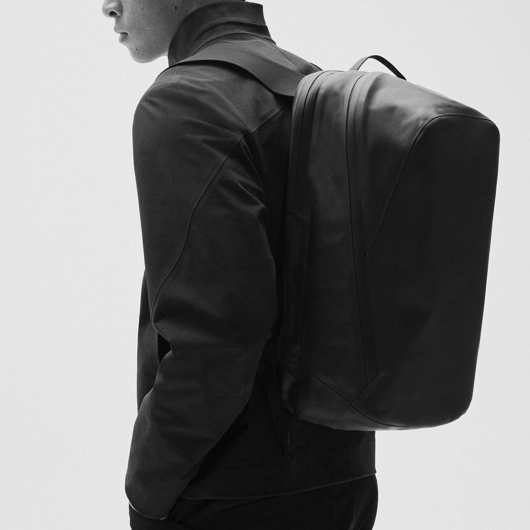 Side view of a person wearing a dark jacket and a sleek black backpack.