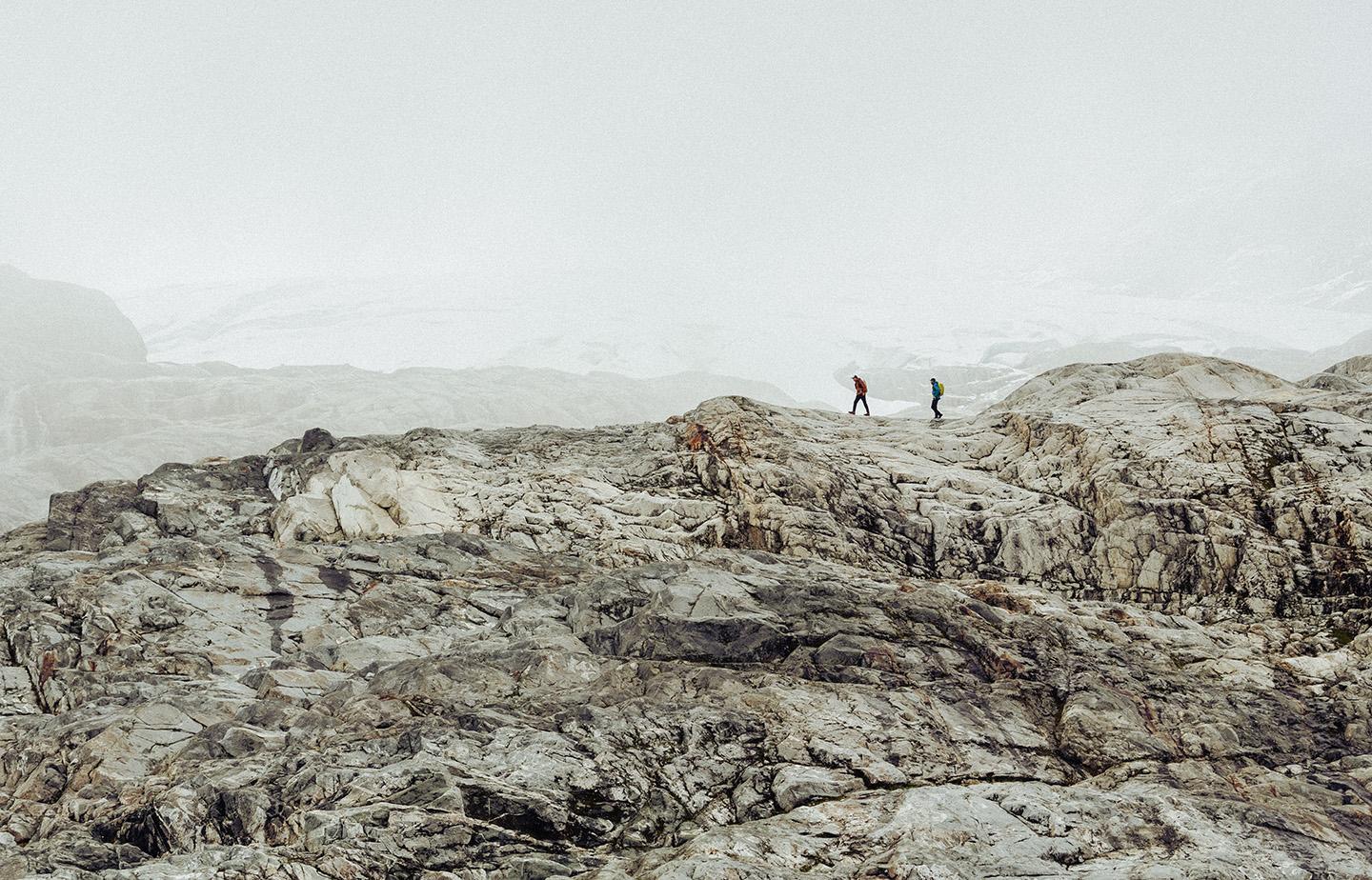 two people are standing on top of a rocky mountain