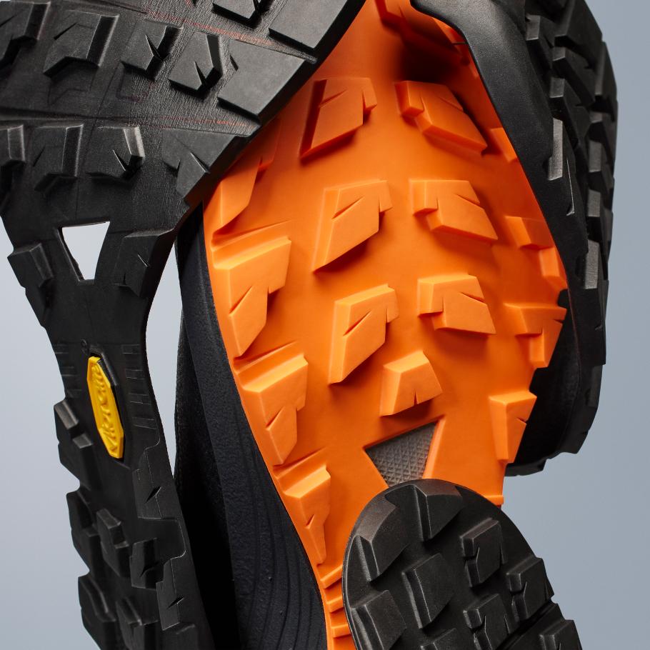 the bottom of a pair of black and orange shoes with a vibram rubber sole