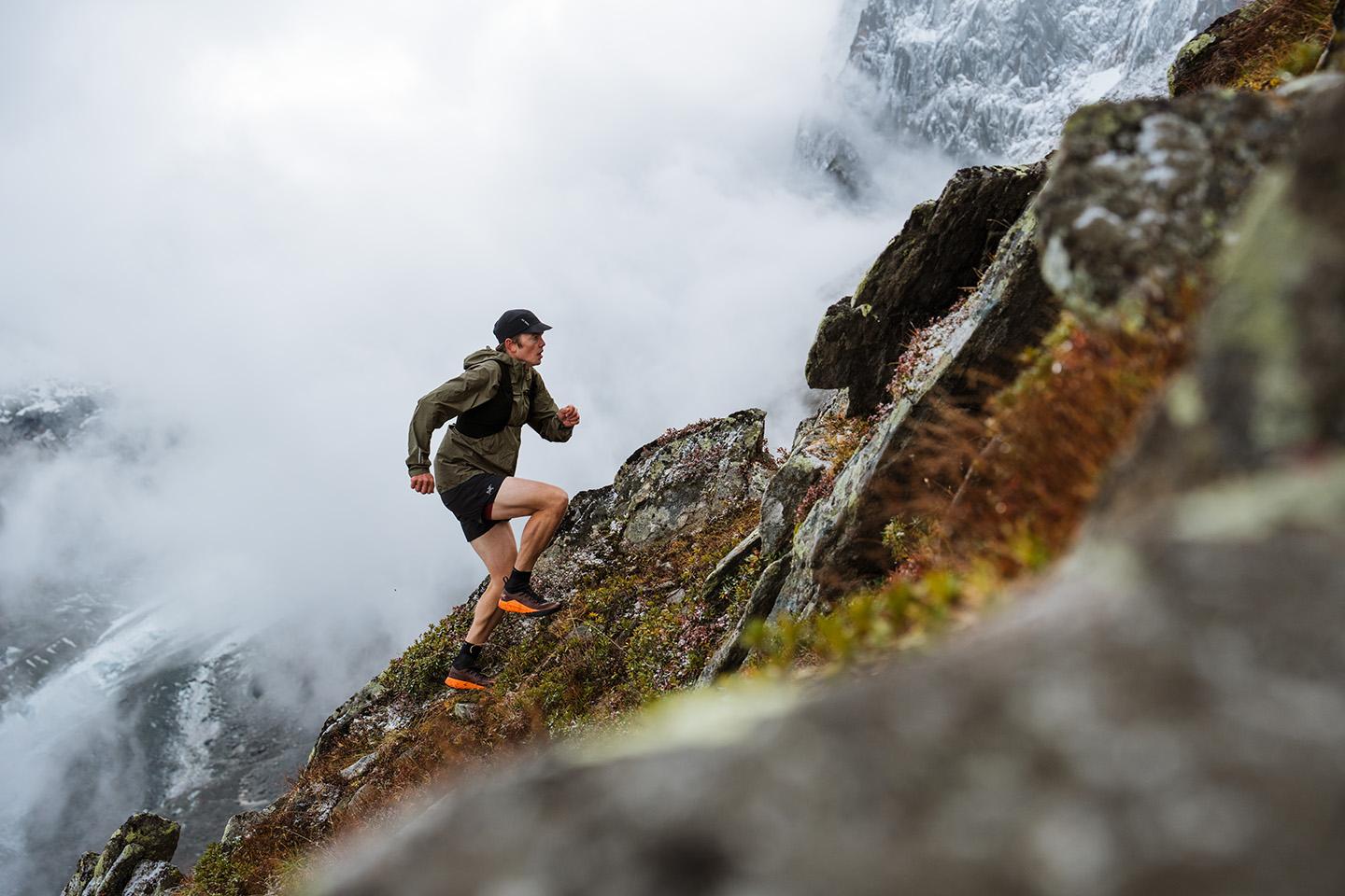 a man in trail running shoes is running down a rocky hillside in the mountains