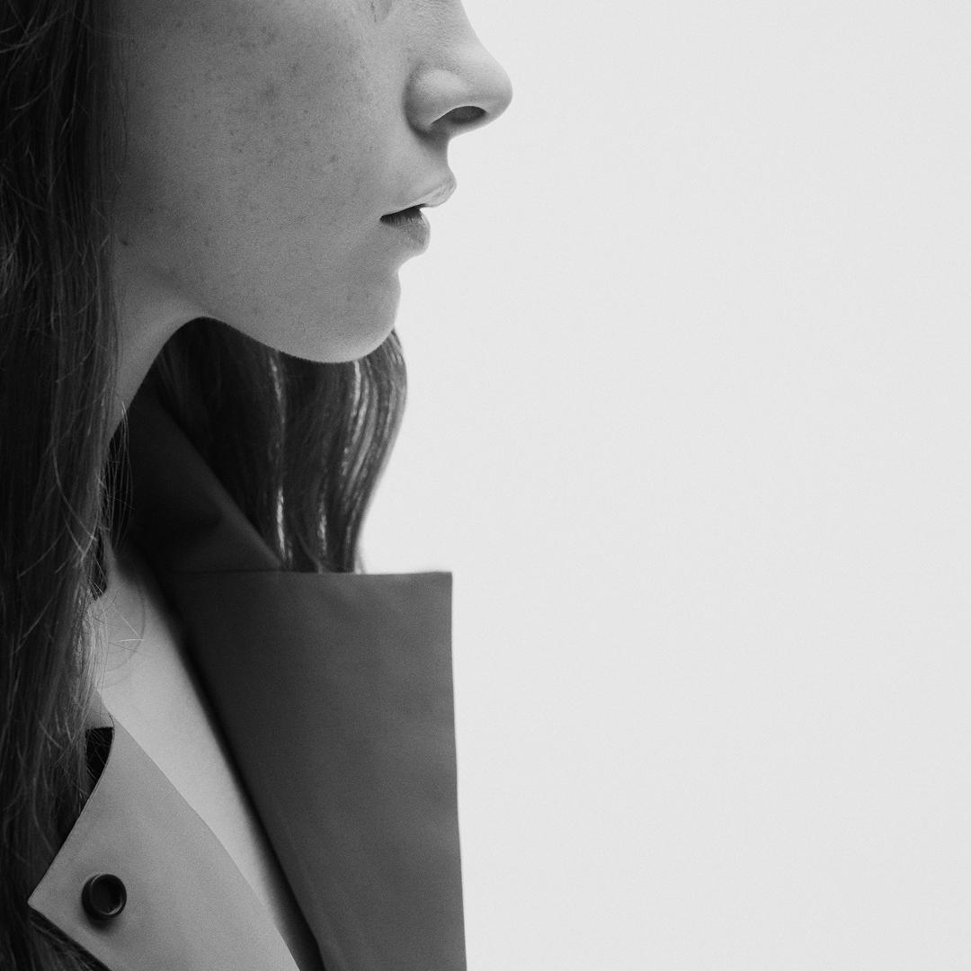 Monochrome side profile of a woman's face and collared jacket.
