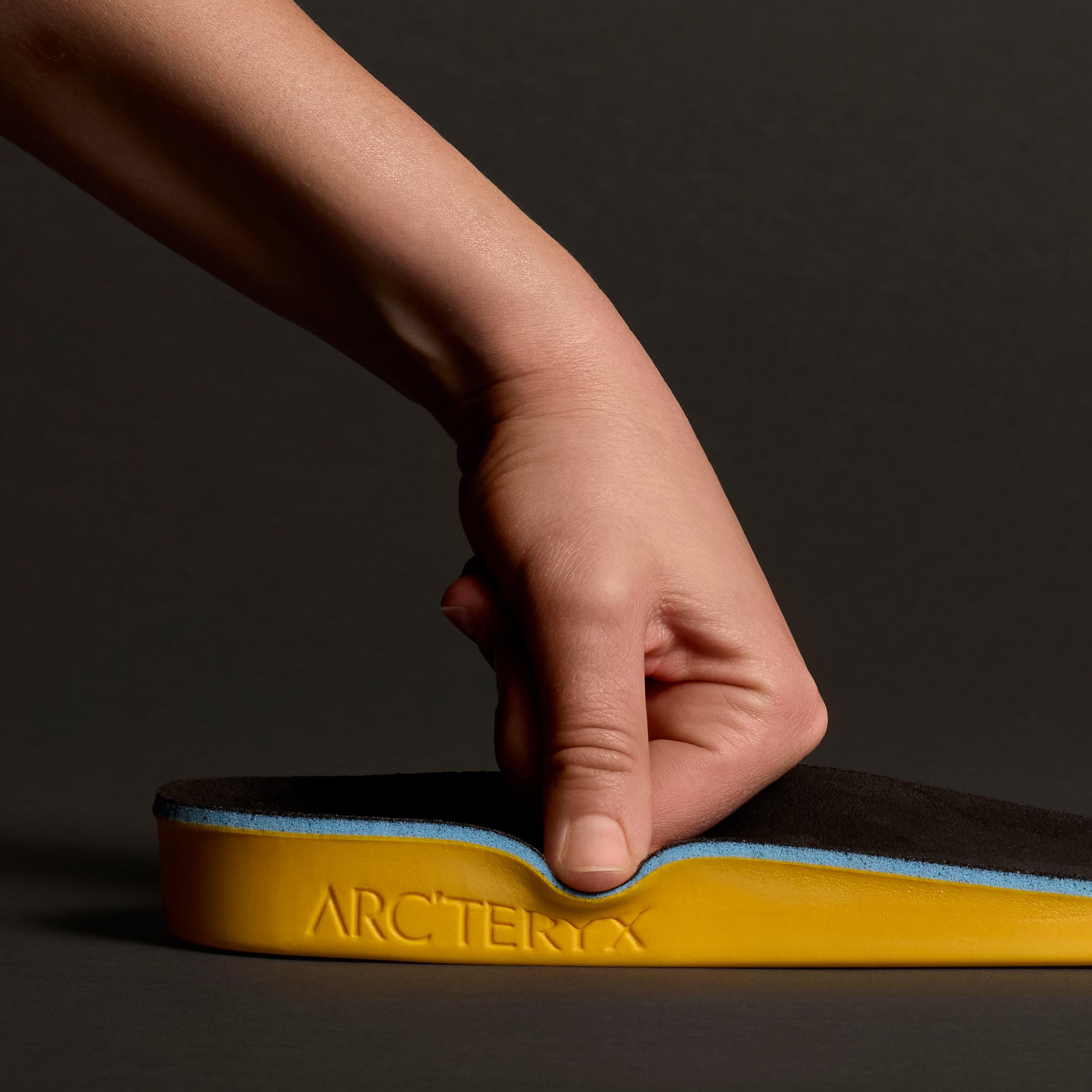 a person is pressing down a yellow Arcteryx insole with their finger
