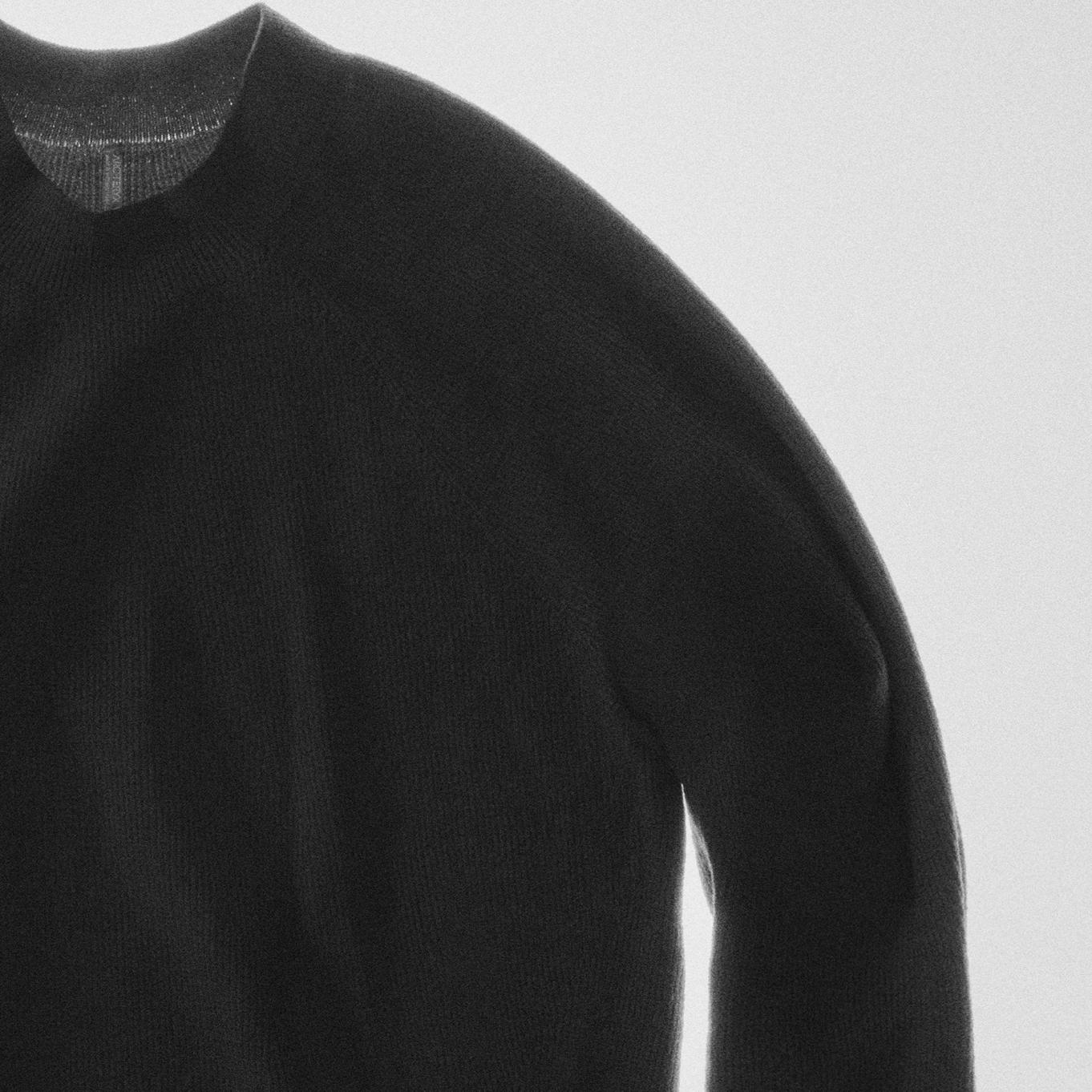 a close up of a black sweater on a white background .