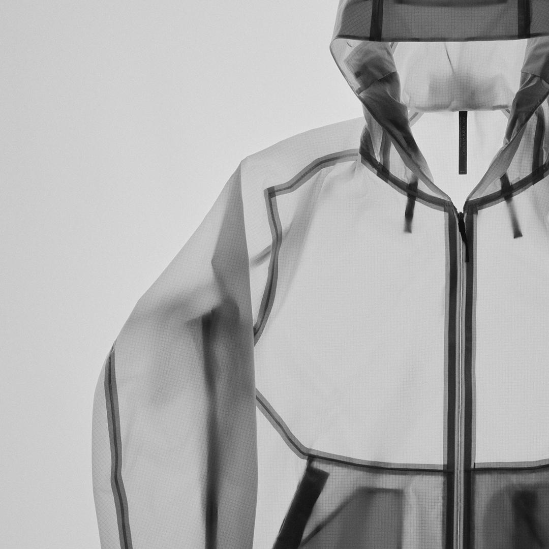 A light gray translucent hooded jacket with dark trim and a front zipper.
