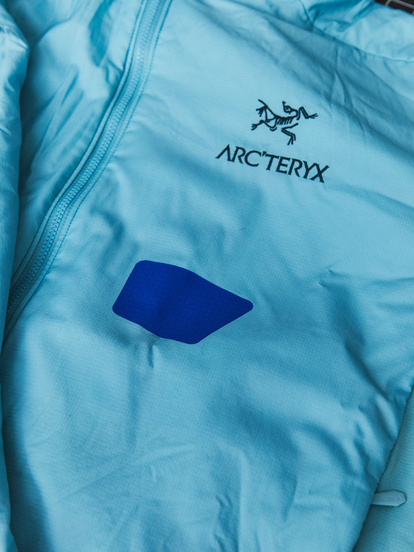 Light blue Arc'teryx jacket with a dark blue diamond patch.