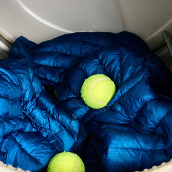 Blue down jacket and two tennis balls in a dryer.