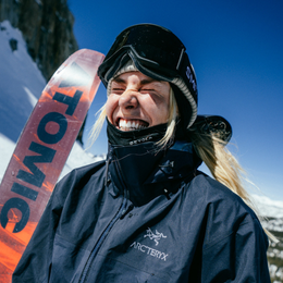 a woman wearing a black arcteryx jacket holds a snowboard