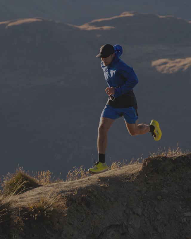 A man trail running on a mountain ridge.