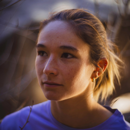a close up of a woman 's face with a purple shirt on