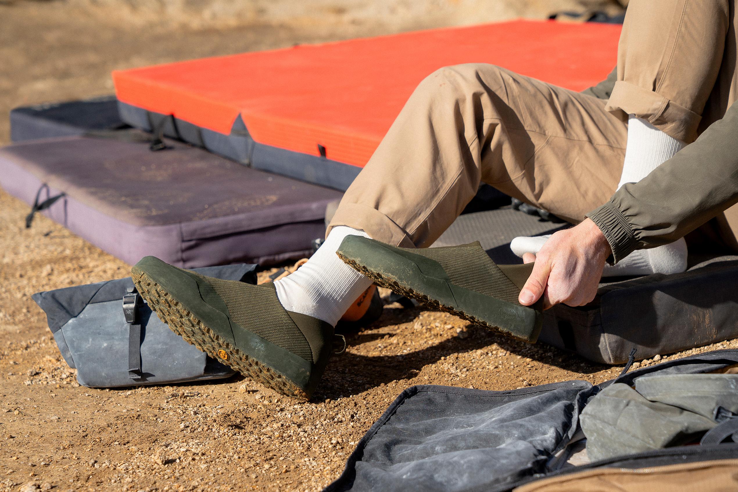 a person is sitting on the ground putting on their shoes .