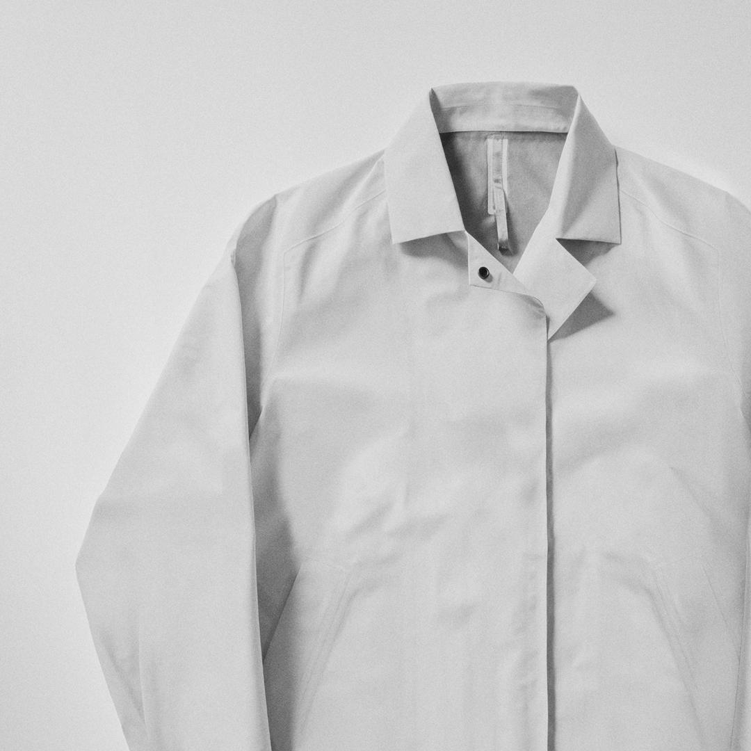 A light gray collared jacket with a single snap closure at the neck.