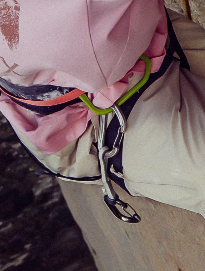 Close-up of a person in a pink top with climbing harness and carabiners.