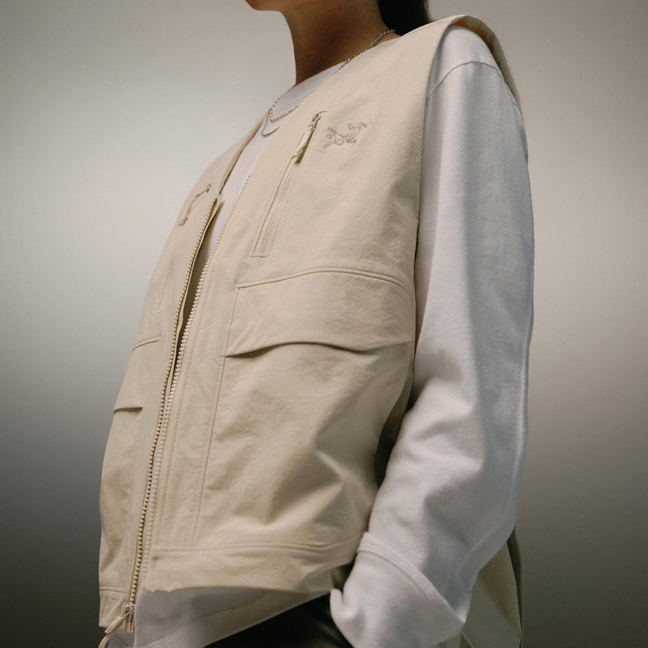 Torso of a person wearing a beige Arc'teryx vest over a white long-sleeve shirt.