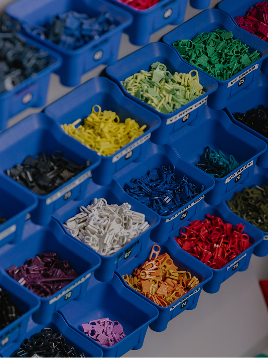 Rows of blue bins filled with small plastic clasps of various colors.