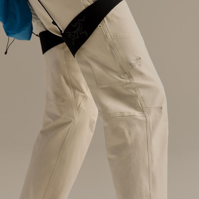 Close-up of a person's legs wearing light-colored Arc'teryx pants, with two visible brand logos.
