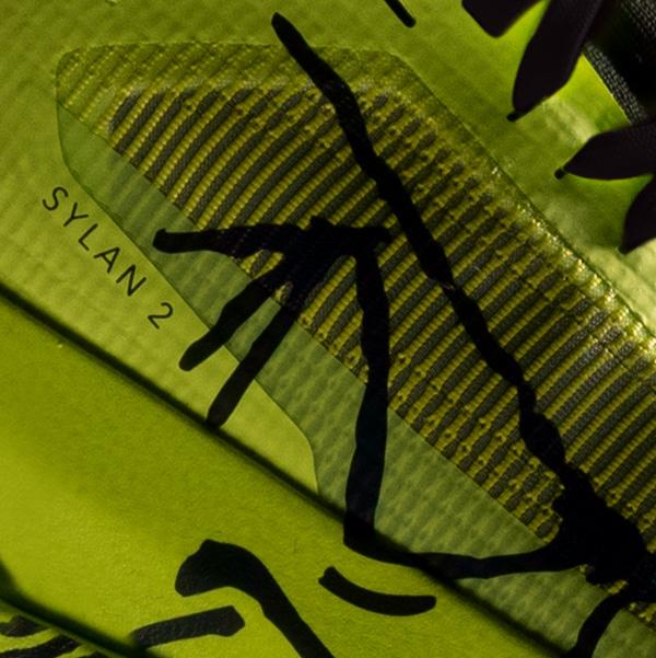 Lime green sneaker detail showing "SYLAN 2" text, black abstract lines, and a textured striped panel.