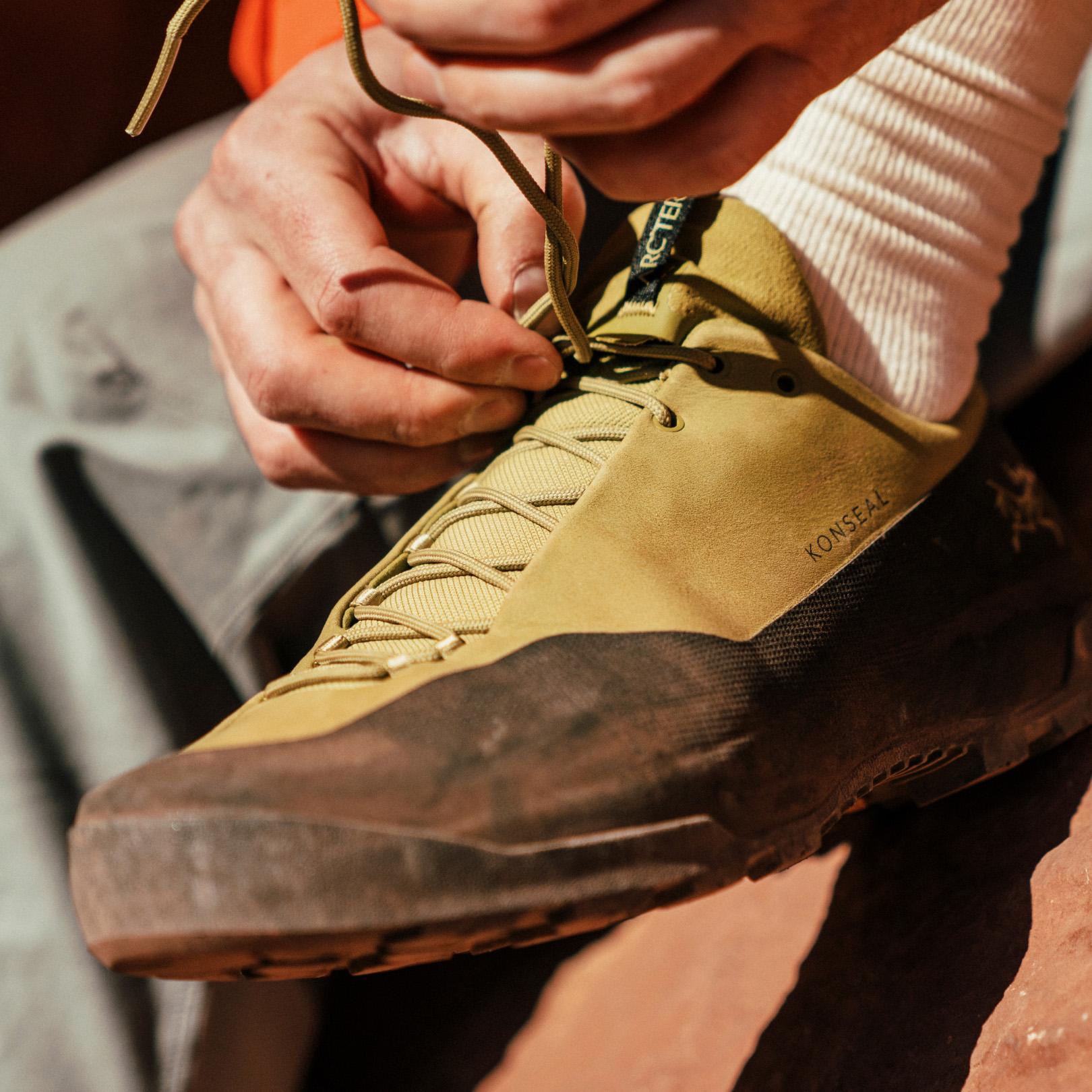 a person is tying their laces on a pair of shoes .