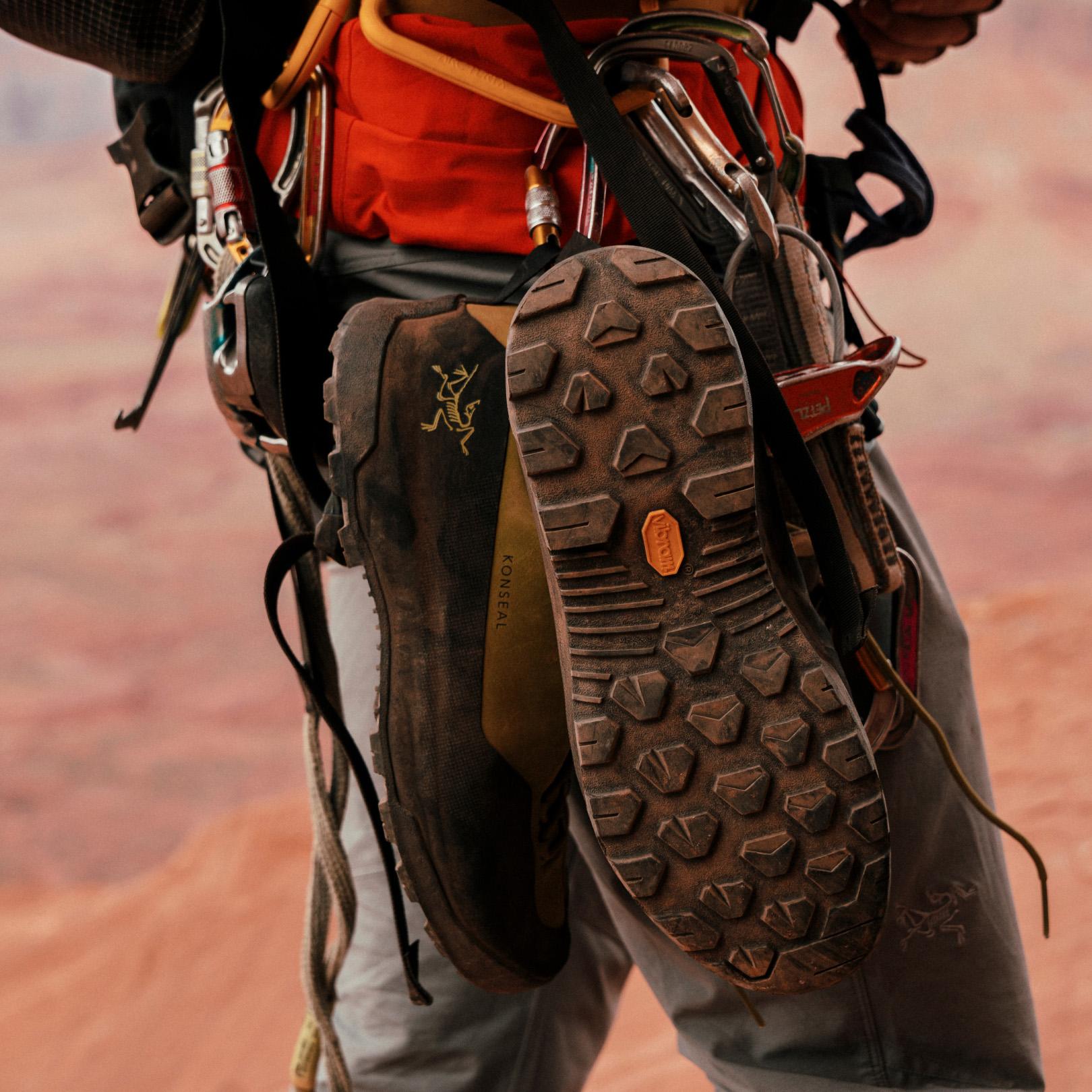 a person is carrying a pair of climbing boots on their back .