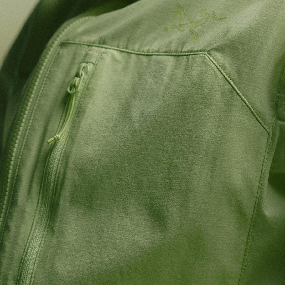 Close-up of a green Arc'teryx jacket with a main zipper, a zippered pocket, and an embroidered logo.