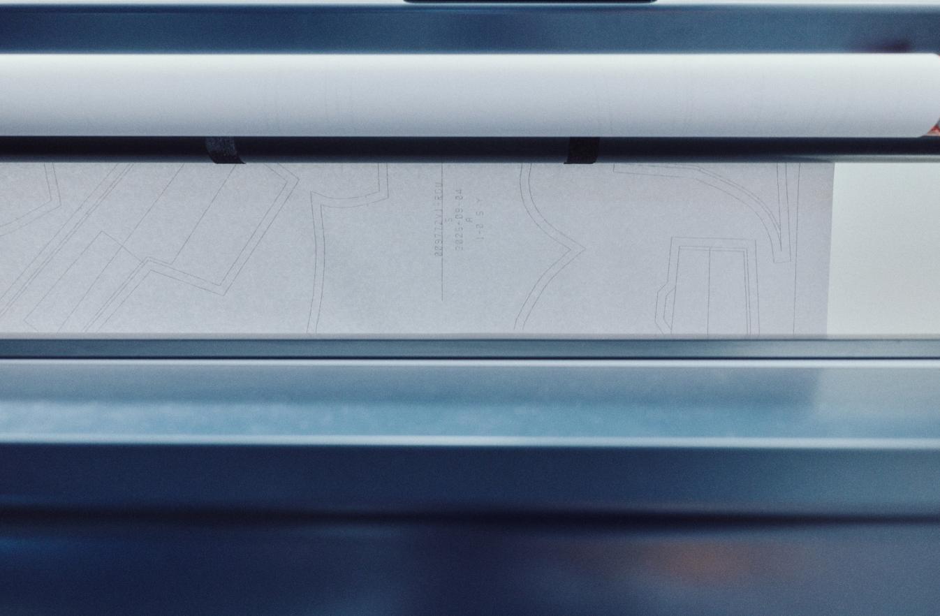White paper with light gray patterns feeds through a printing or scanning machine.