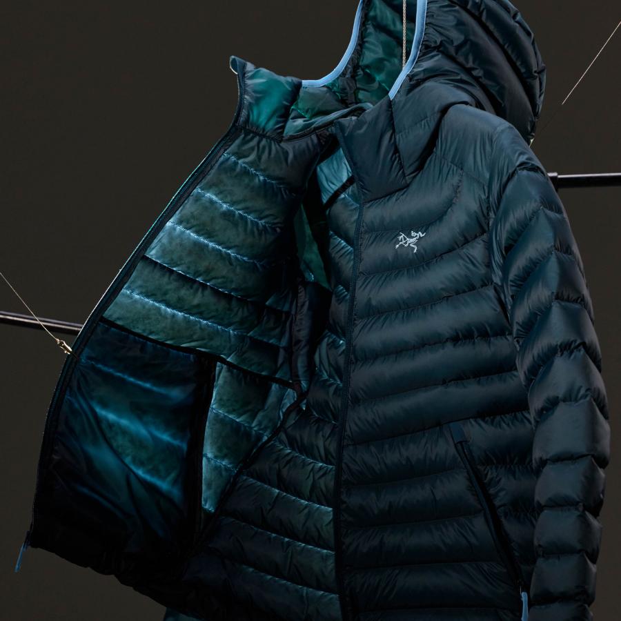 a blue jacket with a hood is hanging on a black background .