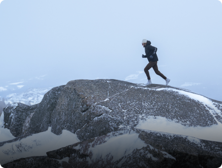 Man running on a snowy mountain peak.