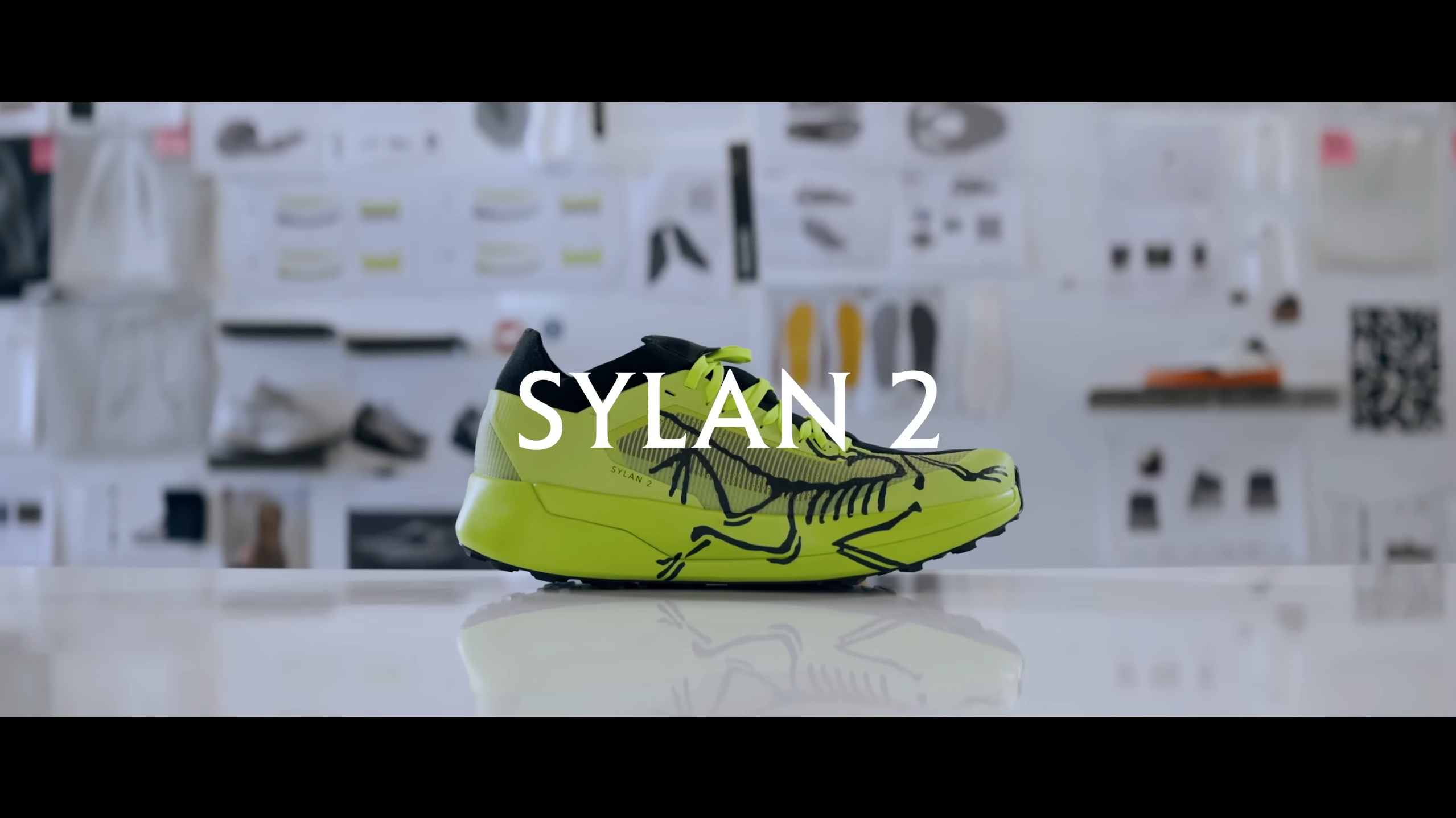 Neon yellow and black running shoe with a skeleton design and "SYLAN 2" text overlay.