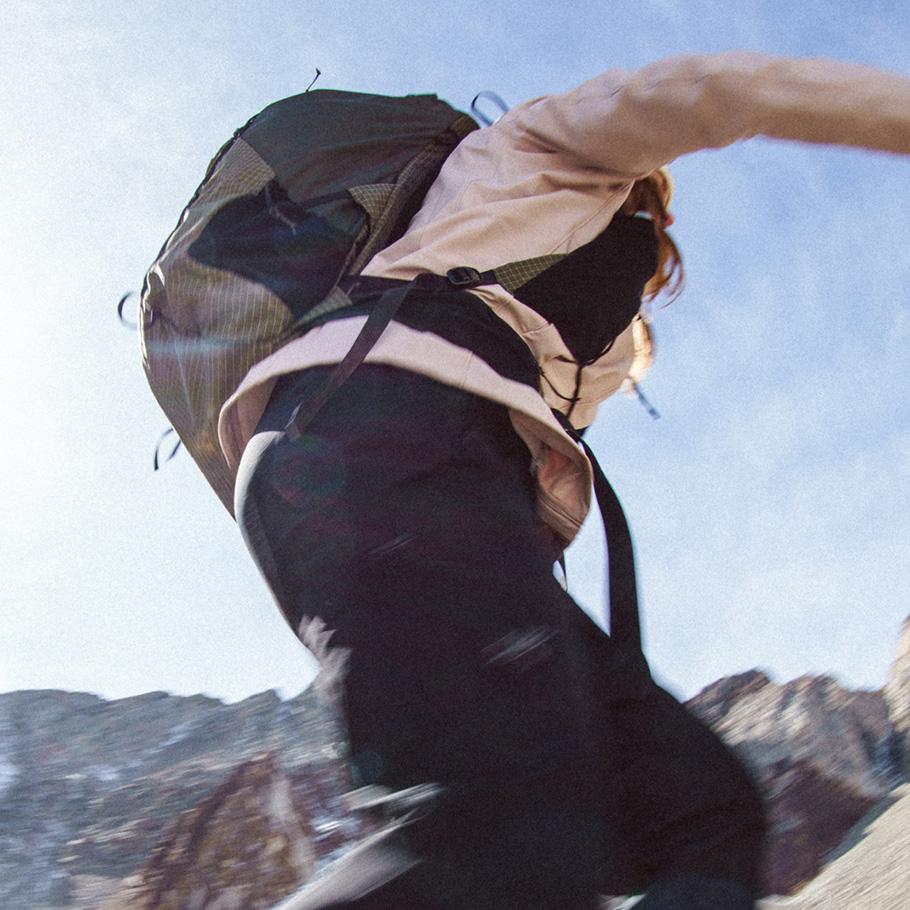 Hiker with a backpack jumping in the mountains.