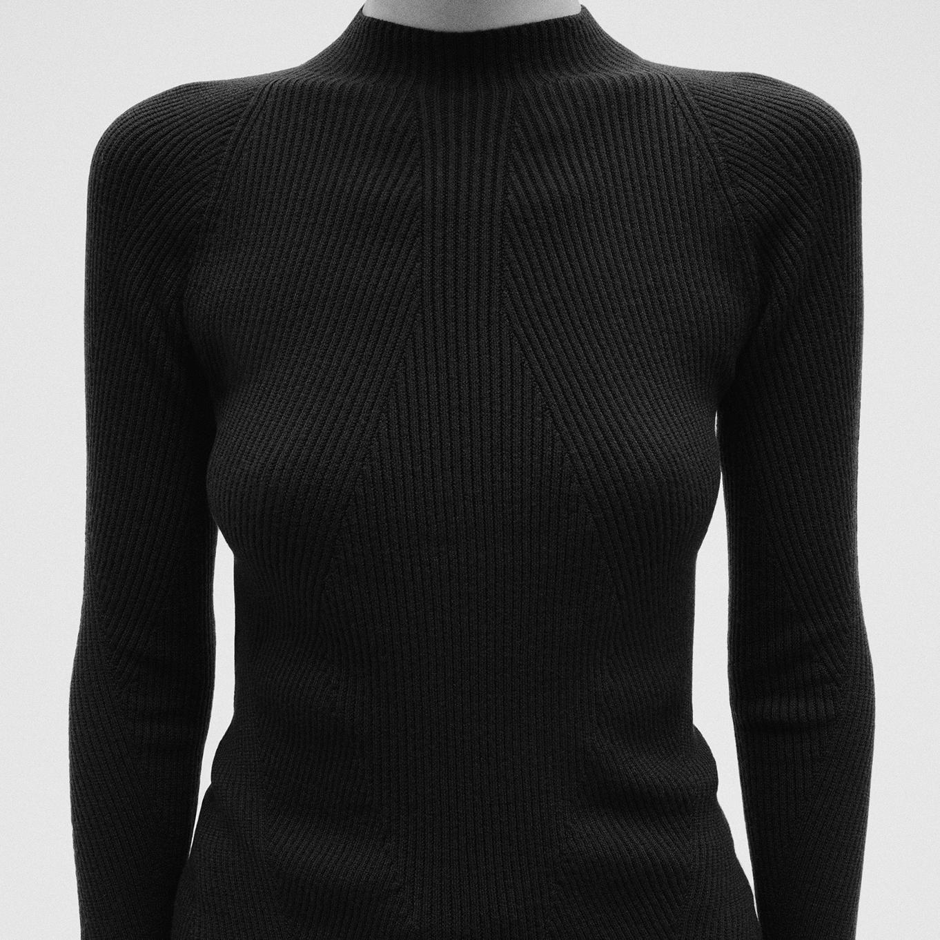 a black sweater with long sleeves and a turtleneck is on a mannequin.