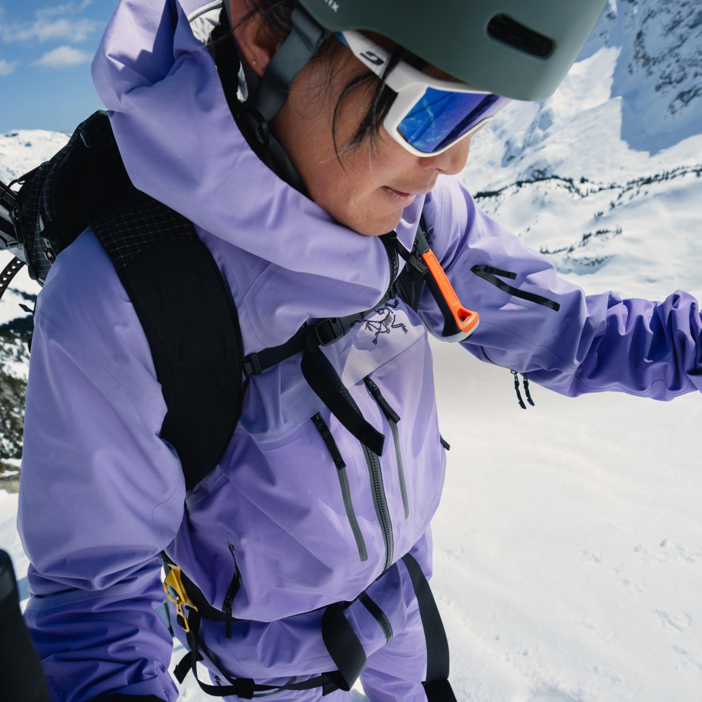 a woman wearing a helmet and goggles is standing in the snow .