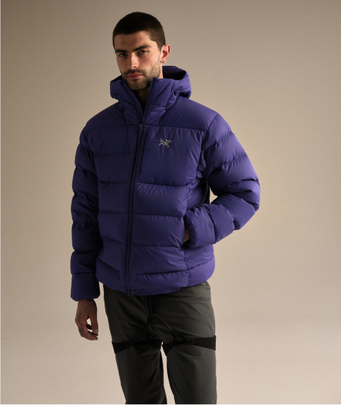 Man wearing a purple Arc'teryx puffer jacket and dark pants.