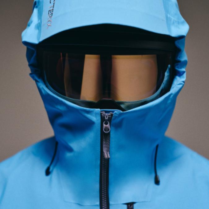 Blue Arc'teryx jacket with hood up and goggles covering the face.