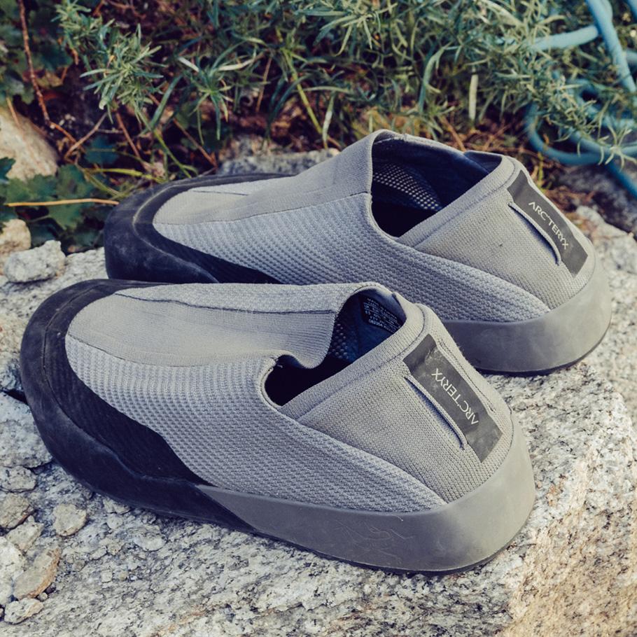 A pair of grey Arc'teryx slip-on approach shoes resting on rocks.