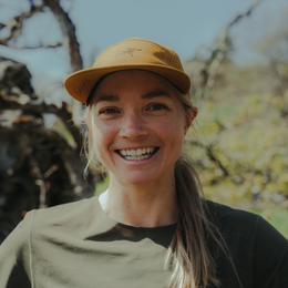 a smiling woman wearing a hat that says arcteryx on it