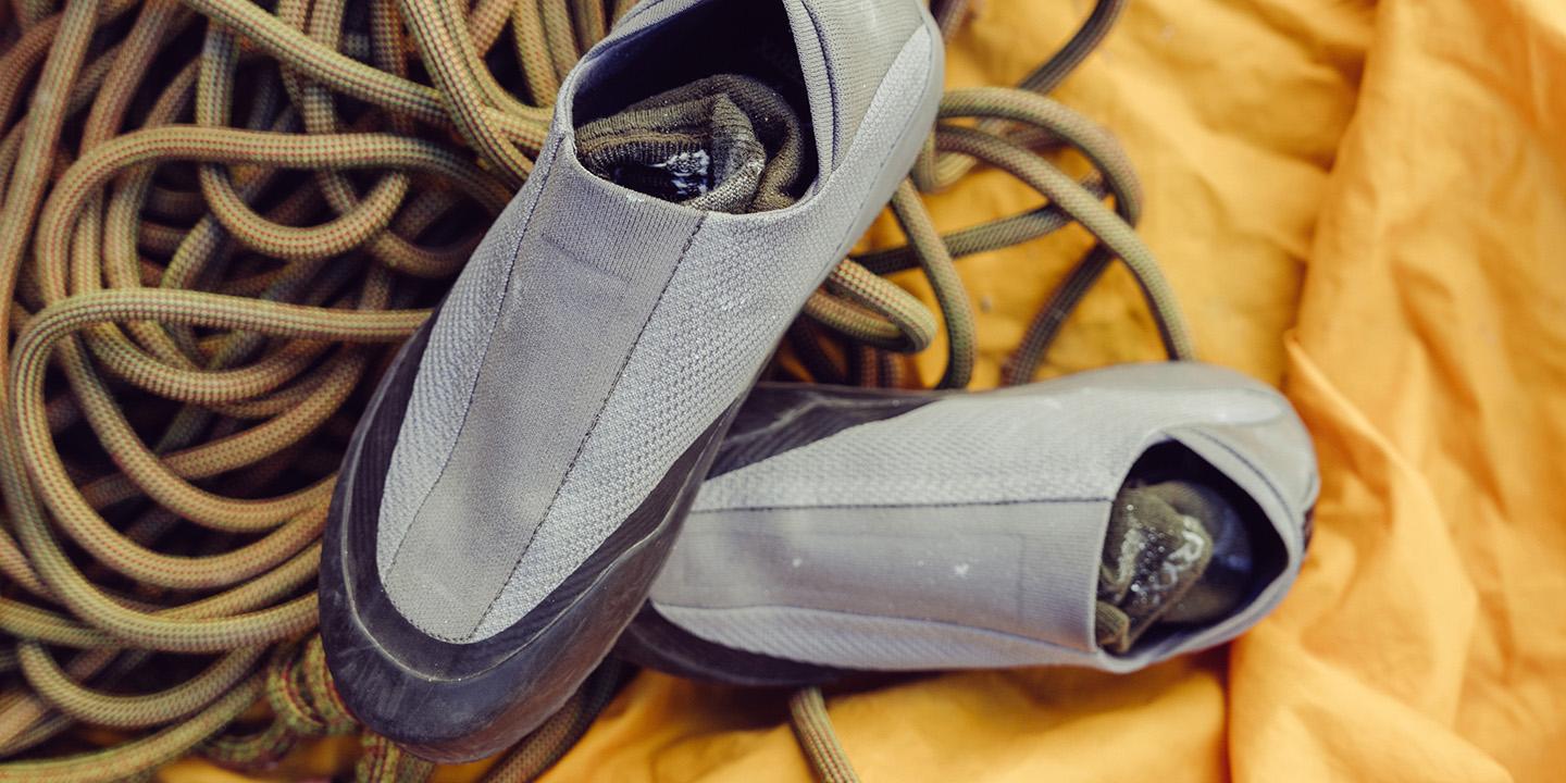 A pair of climbing shoes and a coiled rope on an orange tarp.