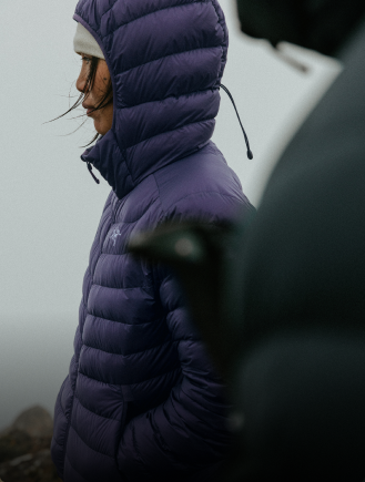 Two people hiking up a rugged mountain with backpacks and trekking poles.