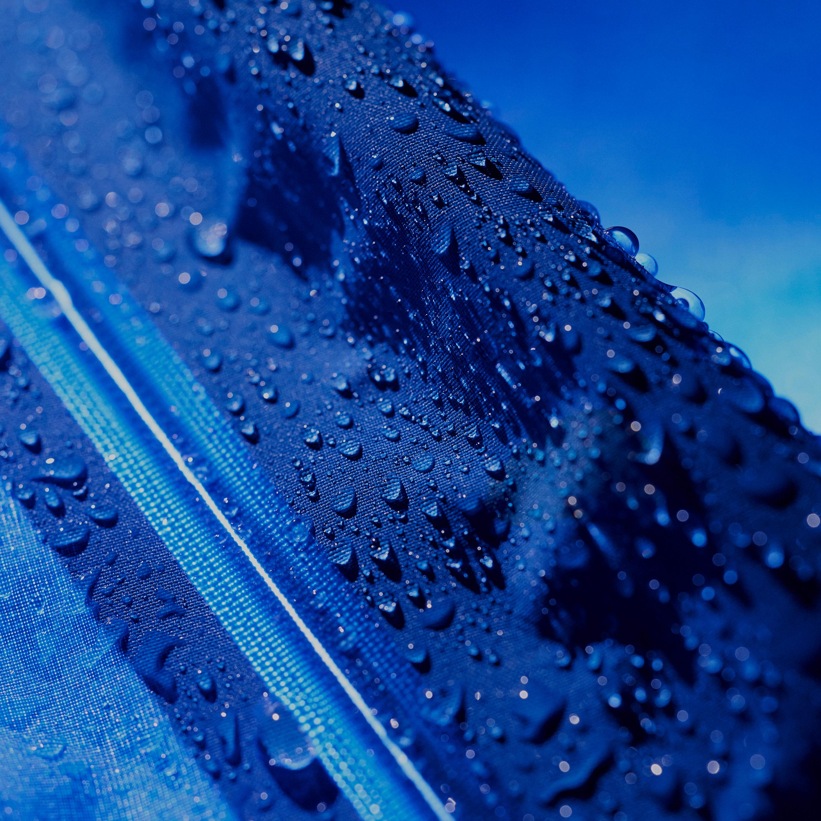 Close-up of water droplets beading on blue waterproof fabric.