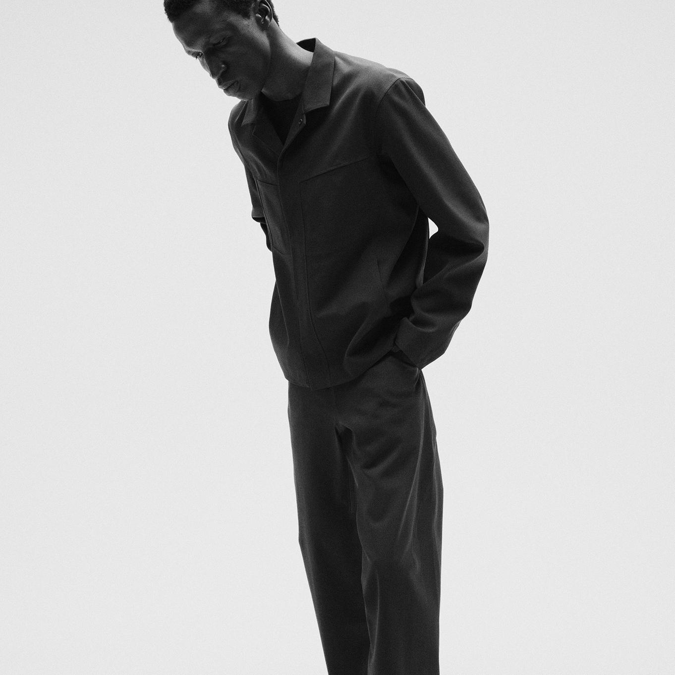 a black and white photo of a man wearing a black jacket and pants.