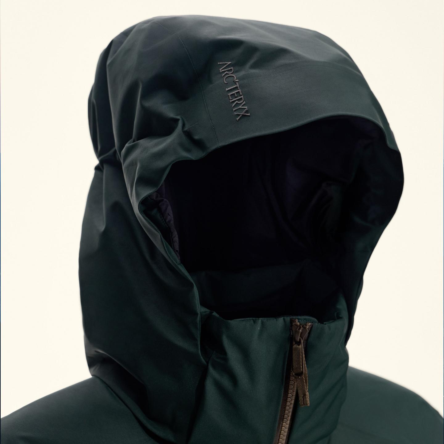 Dark green Arc'teryx jacket with hood up.