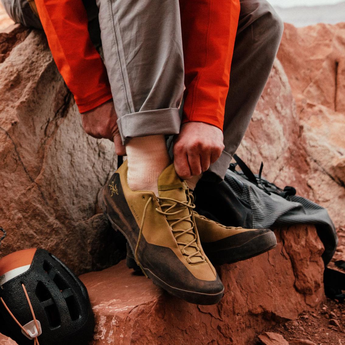 a person is sitting on a rock tying their shoes .