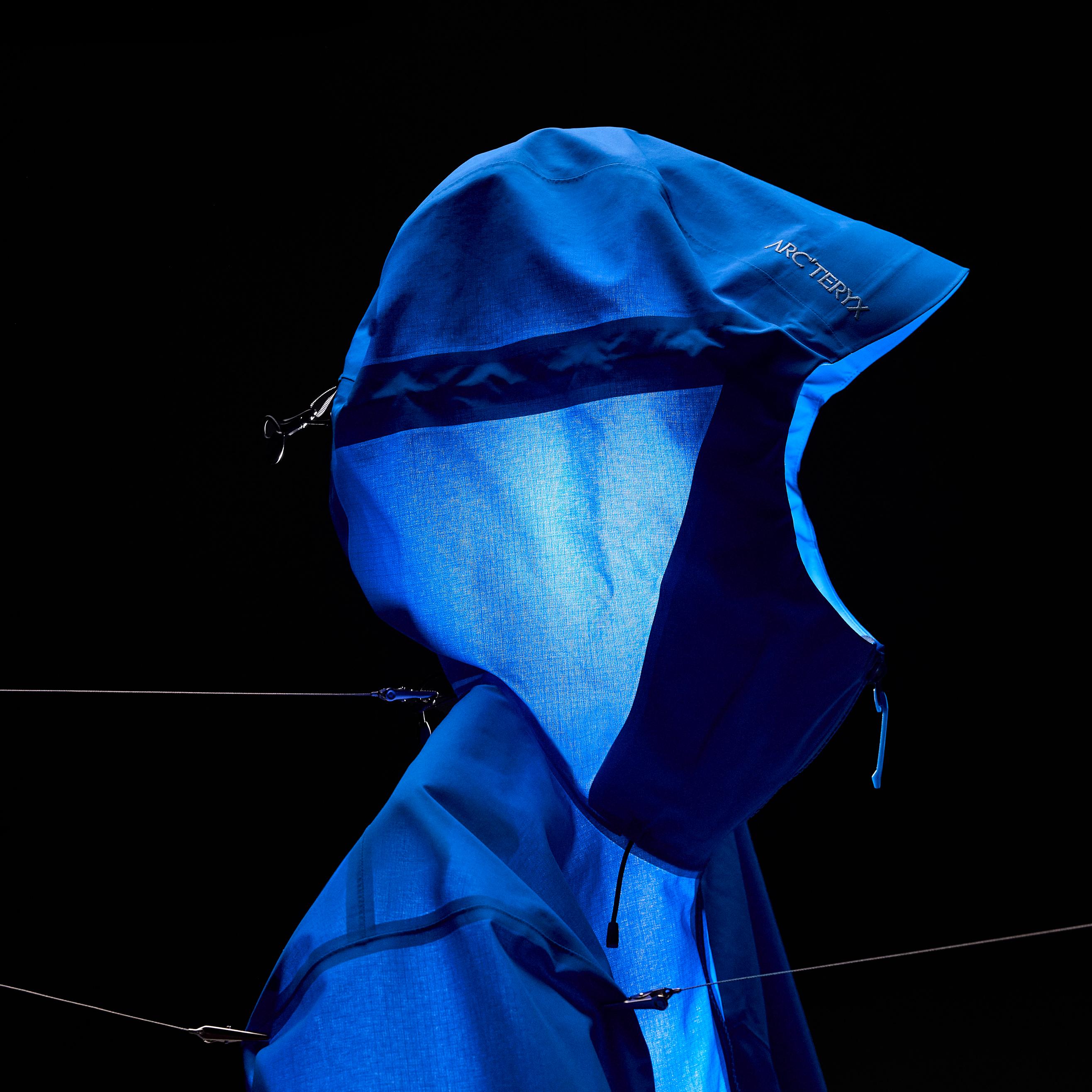 Blue Arc'teryx jacket with illuminated hood against a black background.