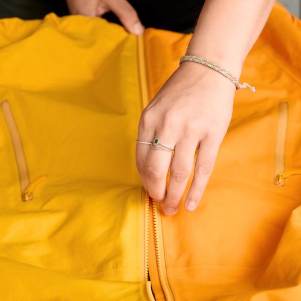 Hands zipping a yellow and orange jacket.