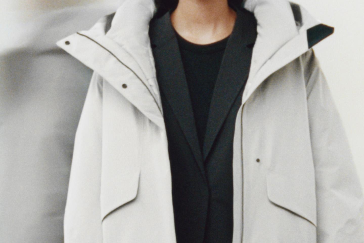 a close up of a person wearing a white insulated shell jacket and a black blazer and shirt