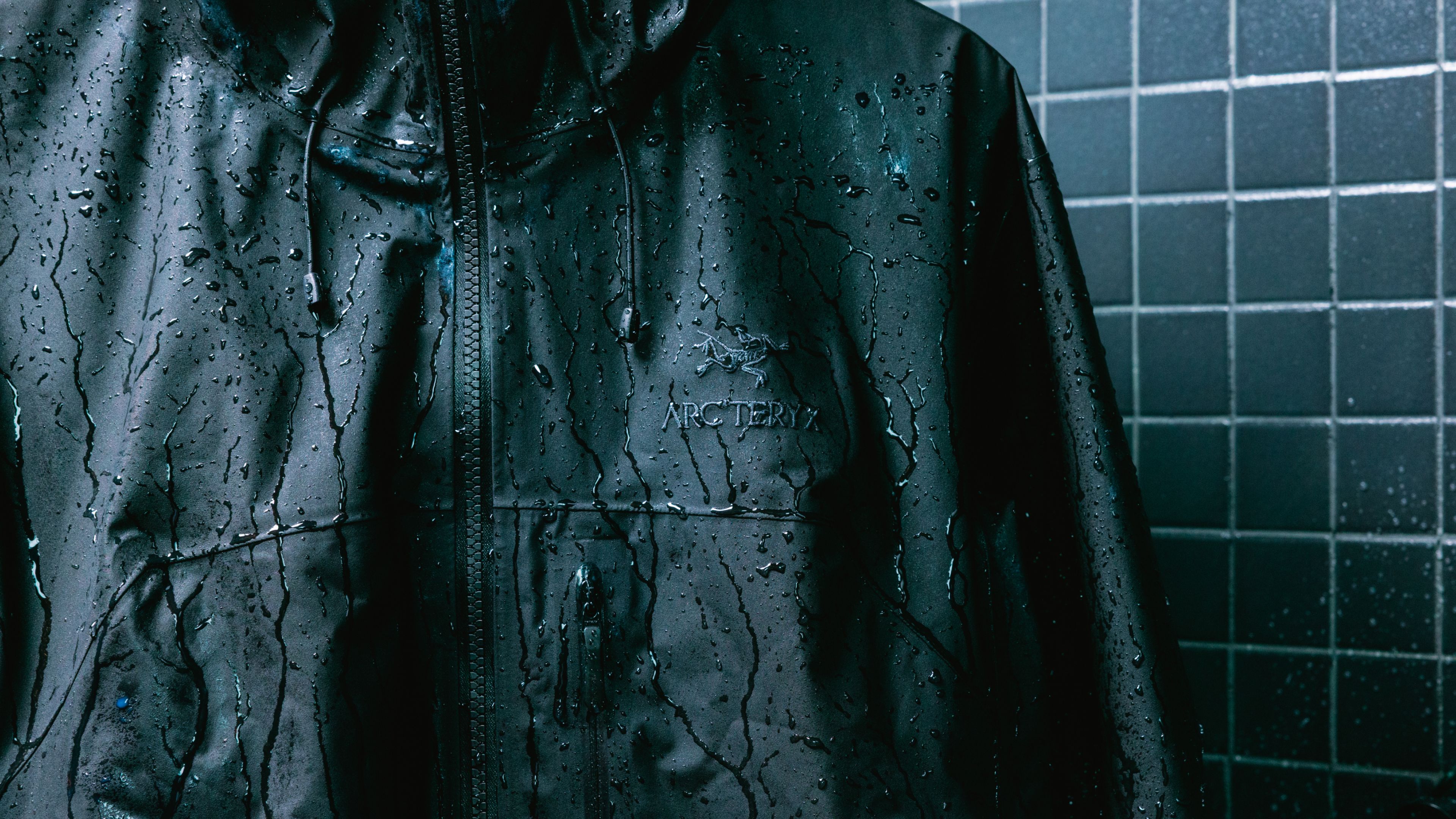 Wet black Arc'teryx jacket against a dark tiled wall.