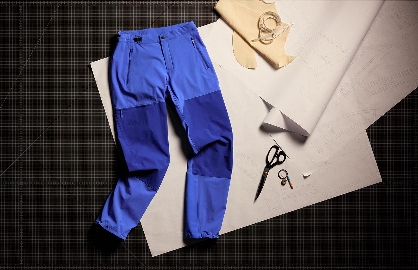 a pair of blue softshell climbing pants is sitting on top of a piece of paper next to scissors