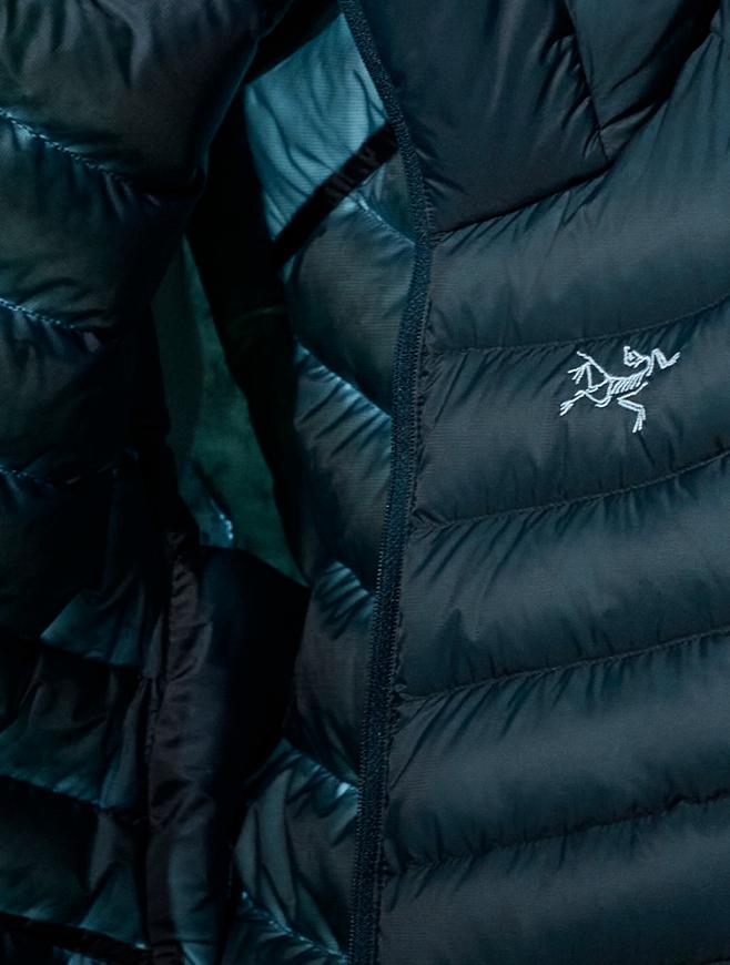 Dark quilted jacket with a zipper and white Arc'teryx logo.